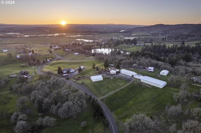 aerial view at dusk with a rural view and a water view