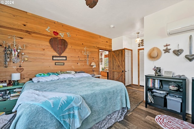 bedroom with a wall mounted air conditioner, wooden walls, and wood finished floors