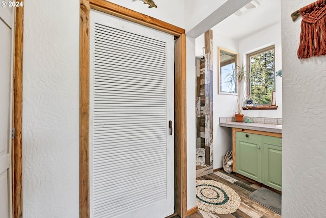 interior space with vanity, a textured wall, a shower stall, and wood finished floors