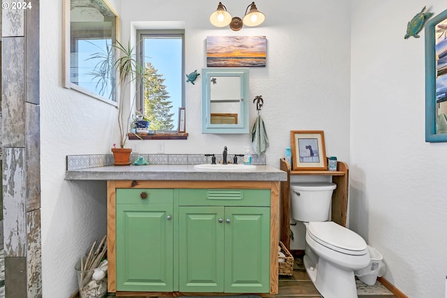 bathroom with vanity, toilet, and a textured wall