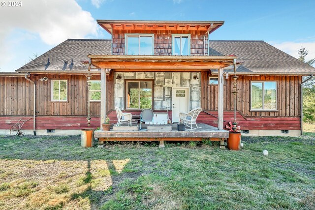 back of property with crawl space, a wooden deck, board and batten siding, a yard, and roof with shingles