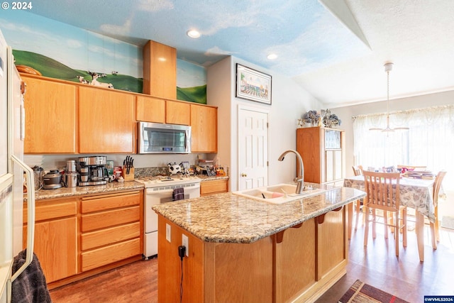 kitchen featuring white range oven, pendant lighting, lofted ceiling, light hardwood / wood-style floors, and a center island with sink