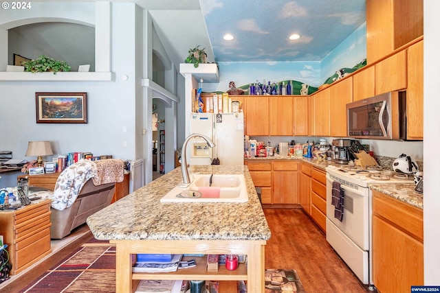 kitchen with sink, dark hardwood / wood-style flooring, white appliances, and a kitchen island with sink