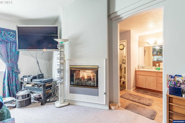 living room with carpet floors, a textured ceiling, and a tiled fireplace