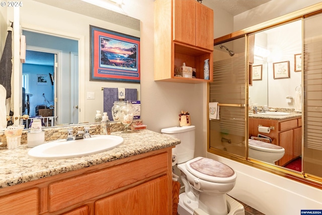 full bathroom featuring toilet, vanity, a textured ceiling, and combined bath / shower with glass door