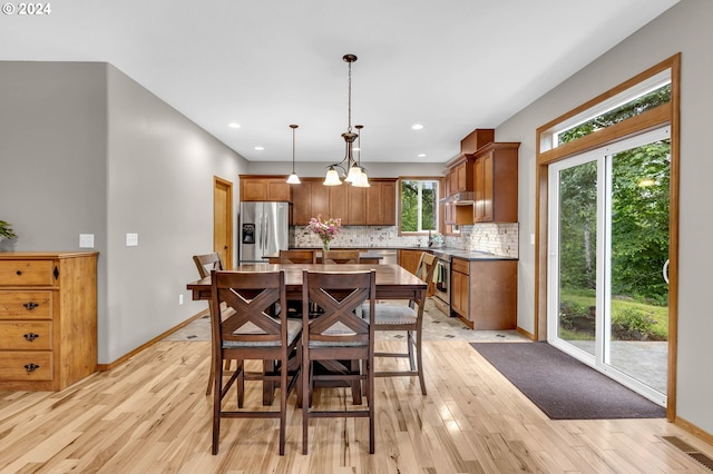 dining area featuring sink, a notable chandelier, and light hardwood / wood-style floors