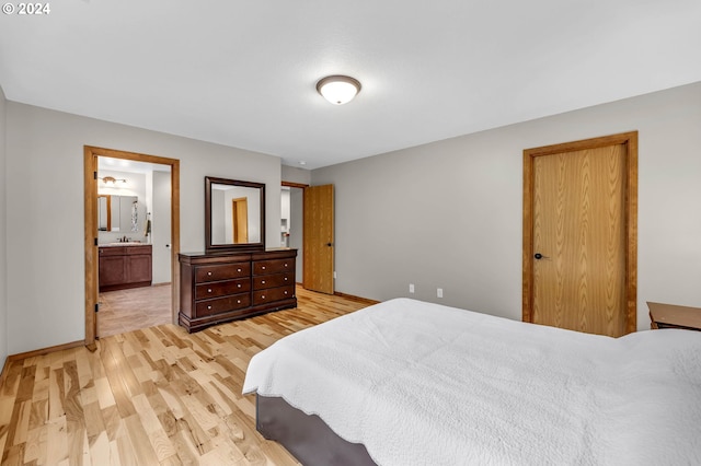 bedroom with sink, ensuite bath, and light hardwood / wood-style flooring