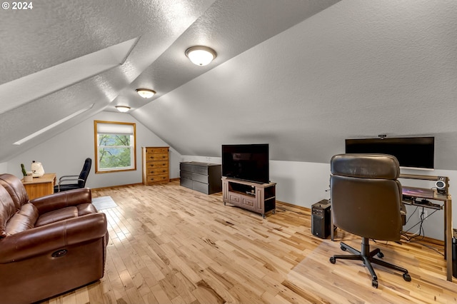 office area with vaulted ceiling, light hardwood / wood-style floors, and a textured ceiling