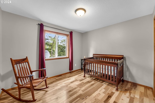 bedroom with light hardwood / wood-style floors and a textured ceiling