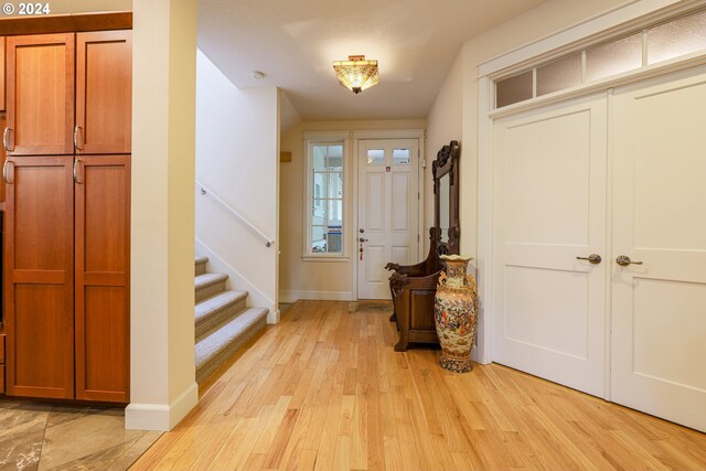 living room featuring light wood-type flooring, a stone fireplace, ceiling fan, and a healthy amount of sunlight