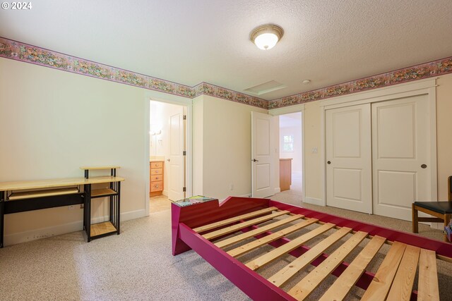 carpeted bedroom featuring a closet, ensuite bath, and a textured ceiling