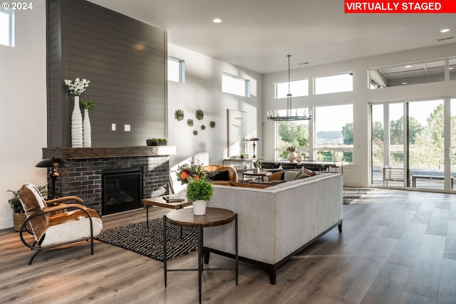 living room with a fireplace, hardwood / wood-style floors, a towering ceiling, and a healthy amount of sunlight