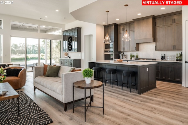 bar with appliances with stainless steel finishes, custom exhaust hood, decorative light fixtures, and light hardwood / wood-style flooring