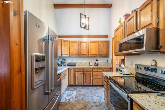 kitchen featuring hanging light fixtures, appliances with stainless steel finishes, a high ceiling, and light stone counters