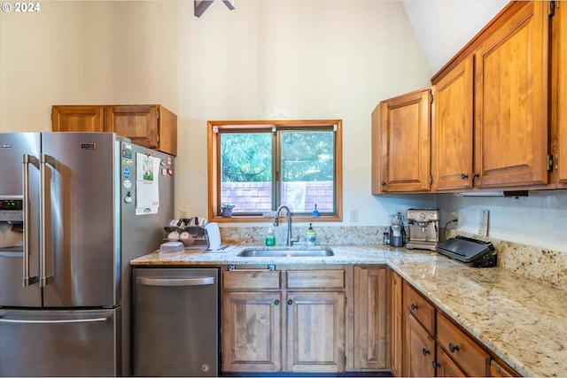 kitchen featuring appliances with stainless steel finishes, sink, lofted ceiling, and light stone counters