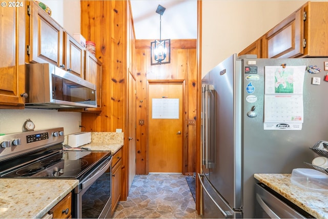 kitchen featuring light stone counters, stainless steel appliances, and decorative light fixtures