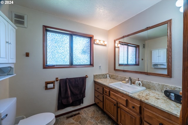 bathroom with vanity, toilet, and a textured ceiling