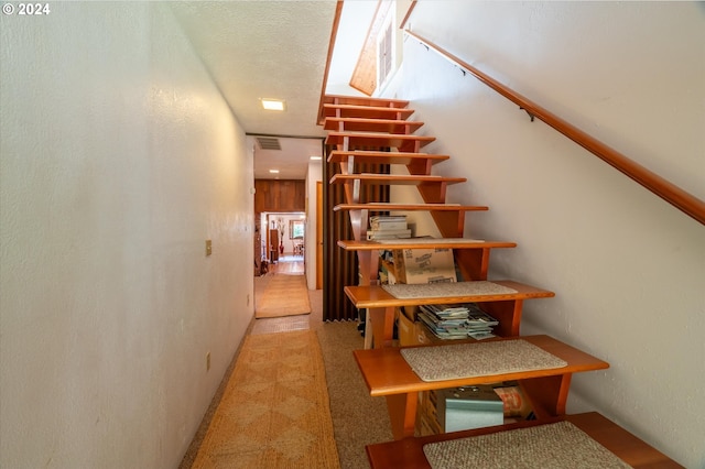 stairway featuring a textured ceiling