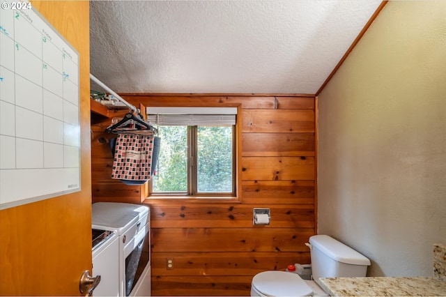 interior space featuring wooden walls, washer and clothes dryer, toilet, and a textured ceiling