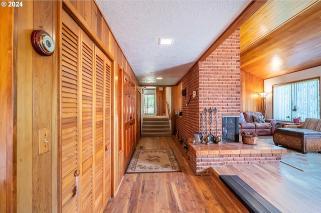 hall with wood-type flooring, vaulted ceiling, and a textured ceiling