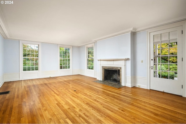 unfurnished living room featuring a wealth of natural light, light hardwood / wood-style floors, and crown molding