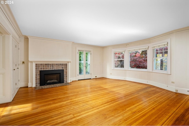 unfurnished living room with hardwood / wood-style flooring, crown molding, and a tile fireplace