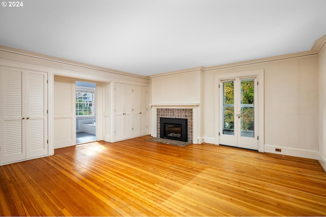 unfurnished living room featuring a fireplace, a wealth of natural light, wood-type flooring, and crown molding