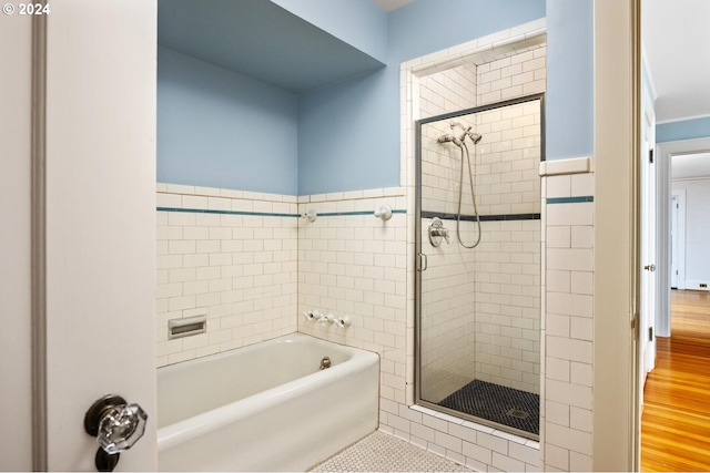 bathroom with tile walls, hardwood / wood-style flooring, and independent shower and bath