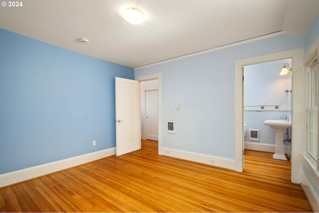 unfurnished bedroom with sink, hardwood / wood-style flooring, and ensuite bath