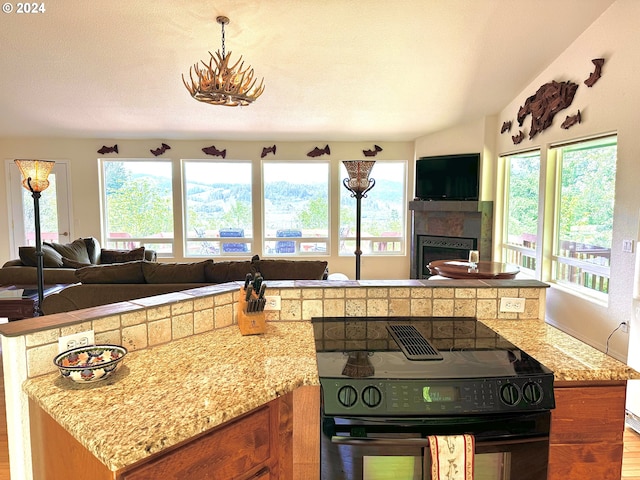 kitchen with light stone counters, black electric range oven, a textured ceiling, and a wealth of natural light