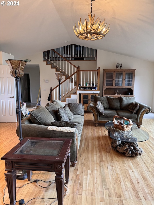 living room featuring an inviting chandelier, lofted ceiling, and light wood-type flooring