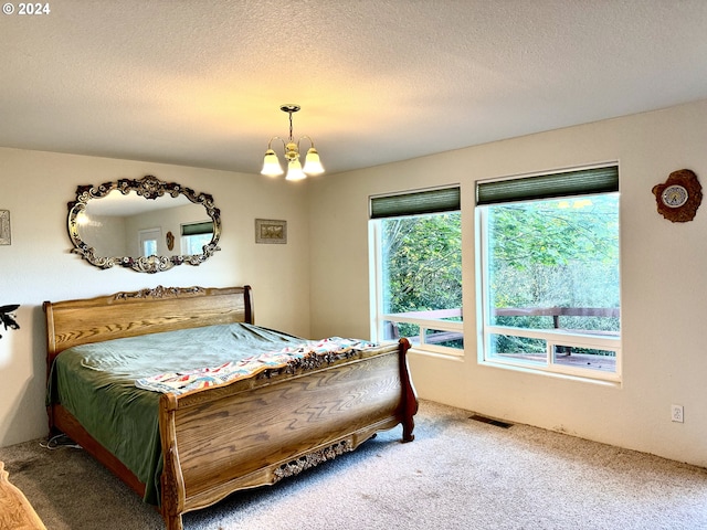 carpeted bedroom with a chandelier and a textured ceiling