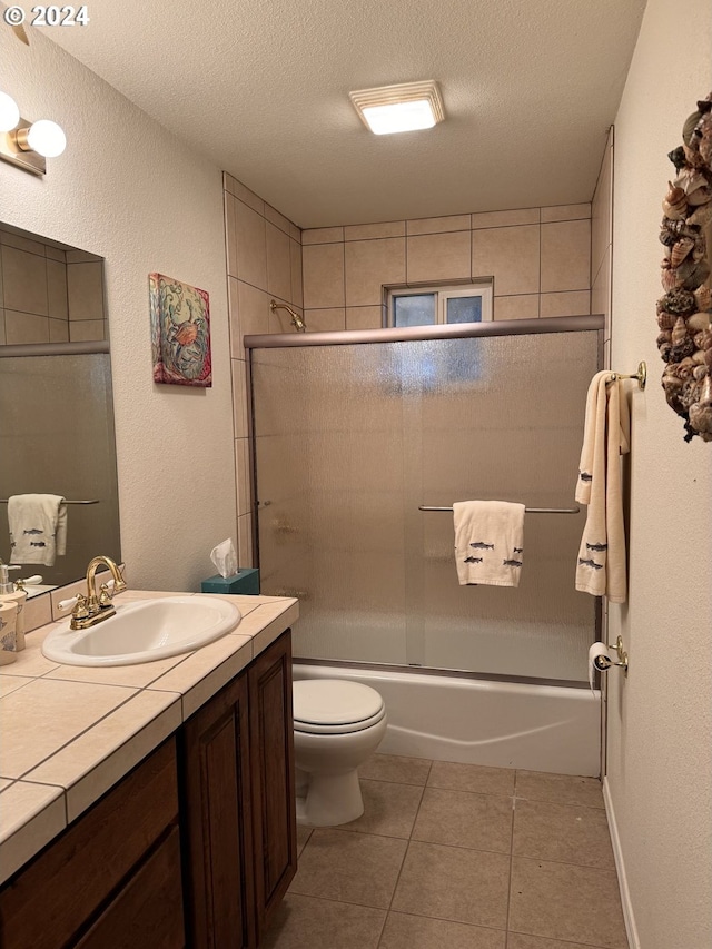 full bathroom with shower / bath combination with glass door, vanity, a textured ceiling, tile patterned floors, and toilet