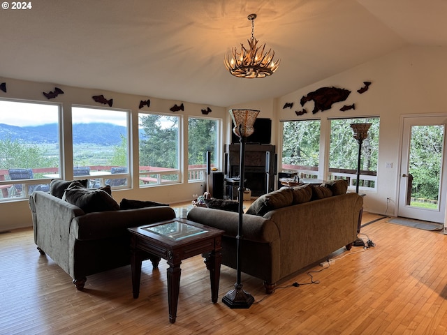 living room with lofted ceiling, a chandelier, and light wood-type flooring