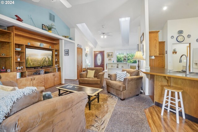 living room with sink, a skylight, light hardwood / wood-style floors, and ceiling fan