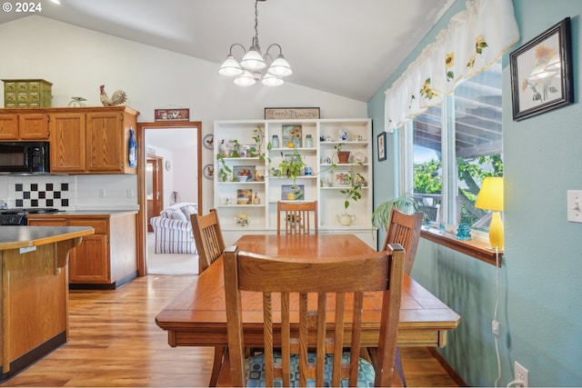 dining room featuring vaulted ceiling, a chandelier, and light hardwood / wood-style flooring