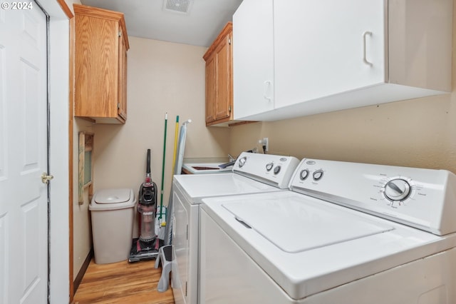 washroom with cabinets, independent washer and dryer, and light hardwood / wood-style flooring