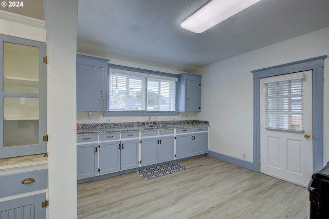 kitchen featuring a sink, light wood-type flooring, baseboards, and blue cabinets