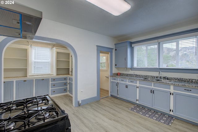 kitchen with black range with gas cooktop, sink, light hardwood / wood-style flooring, and light stone countertops