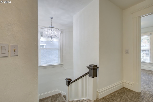 stairs featuring an inviting chandelier, carpet, and baseboards