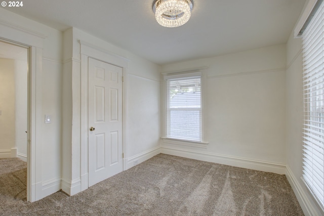 unfurnished bedroom with an inviting chandelier and carpet floors