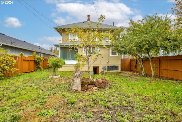 back of property featuring a yard, a fenced backyard, and a sunroom