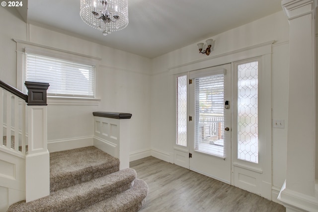 foyer entrance with stairway, a healthy amount of sunlight, wood finished floors, and a chandelier