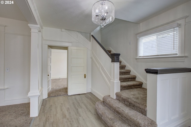 staircase with decorative columns and wood finished floors