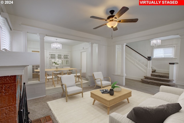 living area with stairway, wood finished floors, baseboards, ornate columns, and ceiling fan with notable chandelier