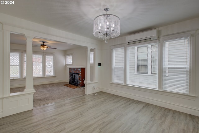 unfurnished living room with decorative columns, a brick fireplace, and a wall unit AC