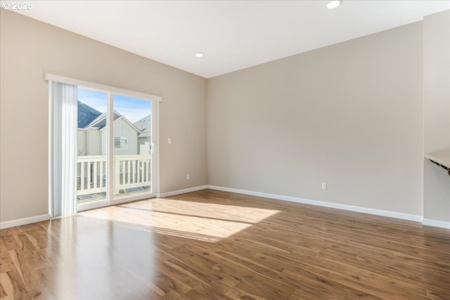 spare room with baseboards, wood finished floors, and recessed lighting