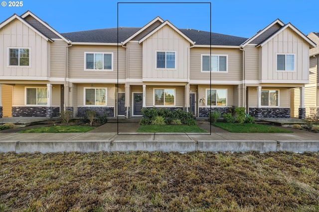 townhome / multi-family property with a shingled roof, board and batten siding, and a front yard