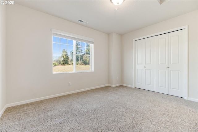 unfurnished bedroom featuring a closet, carpet flooring, visible vents, and baseboards