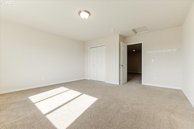 unfurnished bedroom with attic access, a closet, baseboards, and carpet flooring